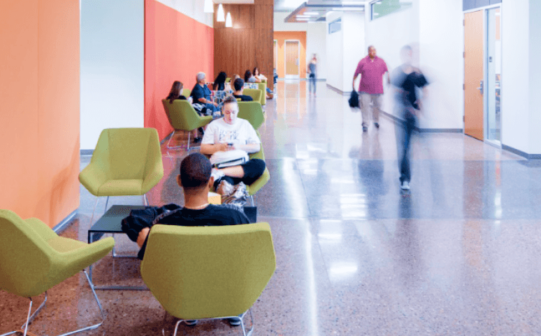 students sitting in hallway, with people walking next to them