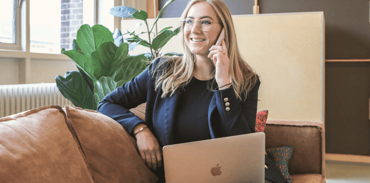 woman on phone with laptop open in lap