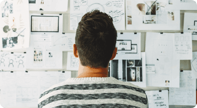 A man looking at an idea board full of notes.