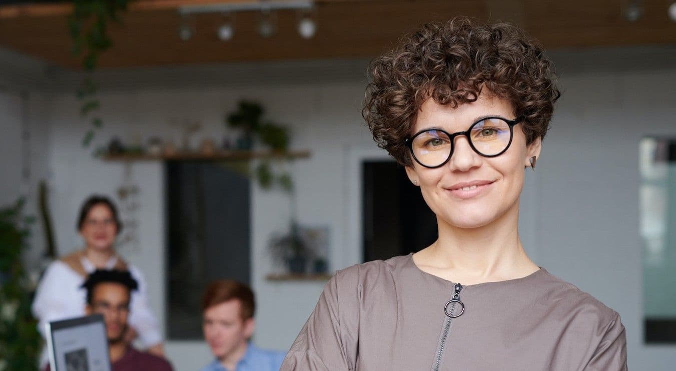 Woman smiling with employees behind her