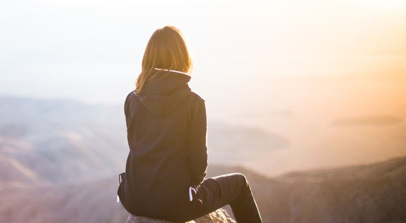 Woman overlooking valley at sunset from vantage point