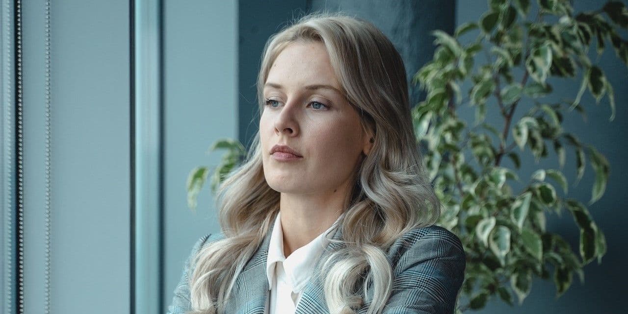 Corporate business woman looking out window unhappy