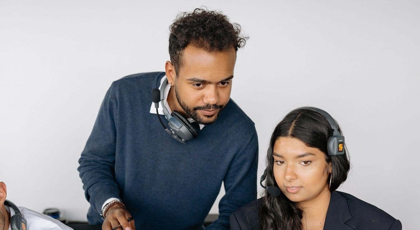 Three individuals wearing headsets, engaged in a professional setting at a call center.