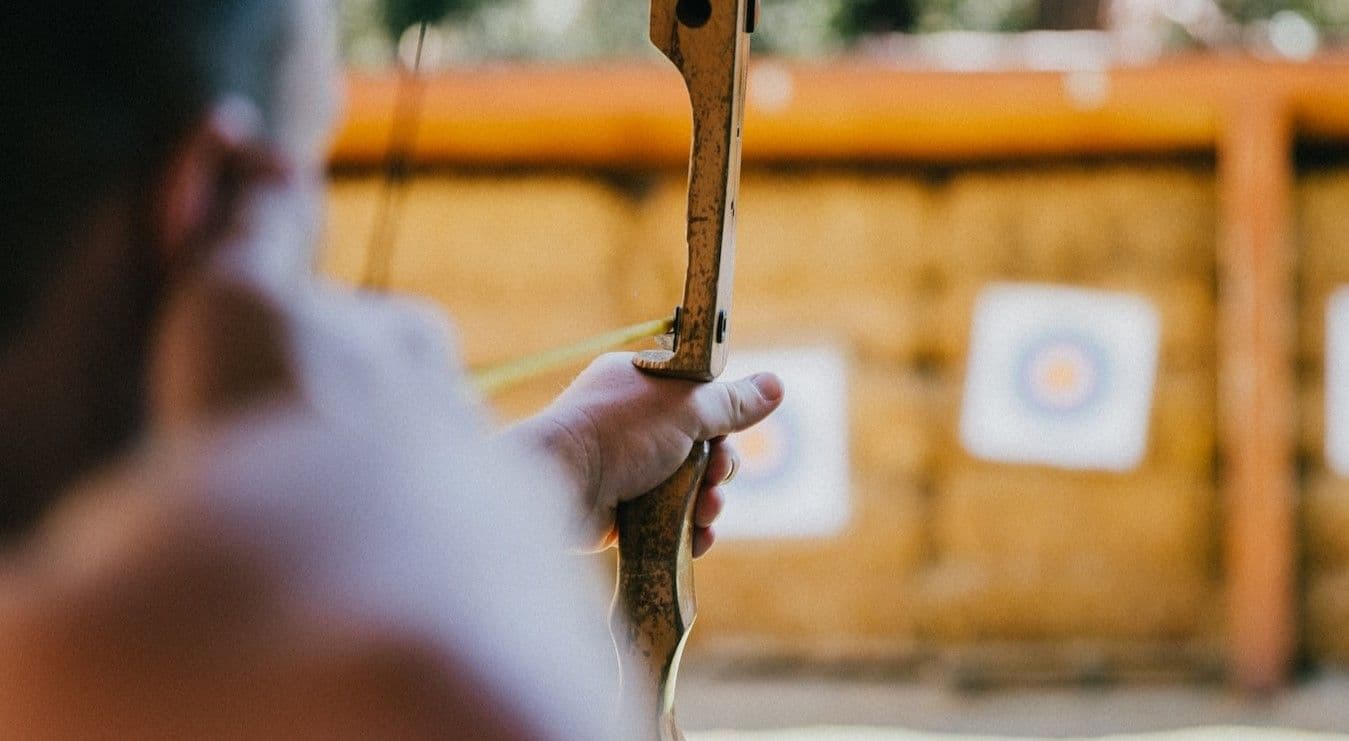 Man aiming bow and arrow at target 