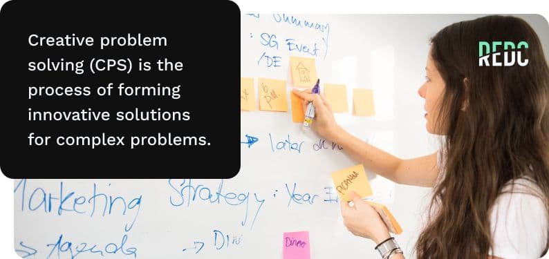 A woman arranging post-it notes and written ideas on a whiteboard. 