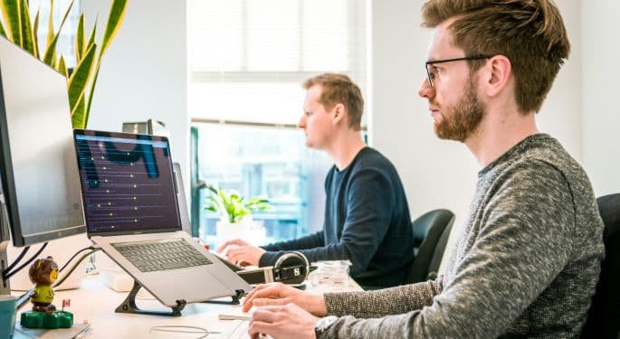 Image: Two digital marketers working next to each other on their laptops